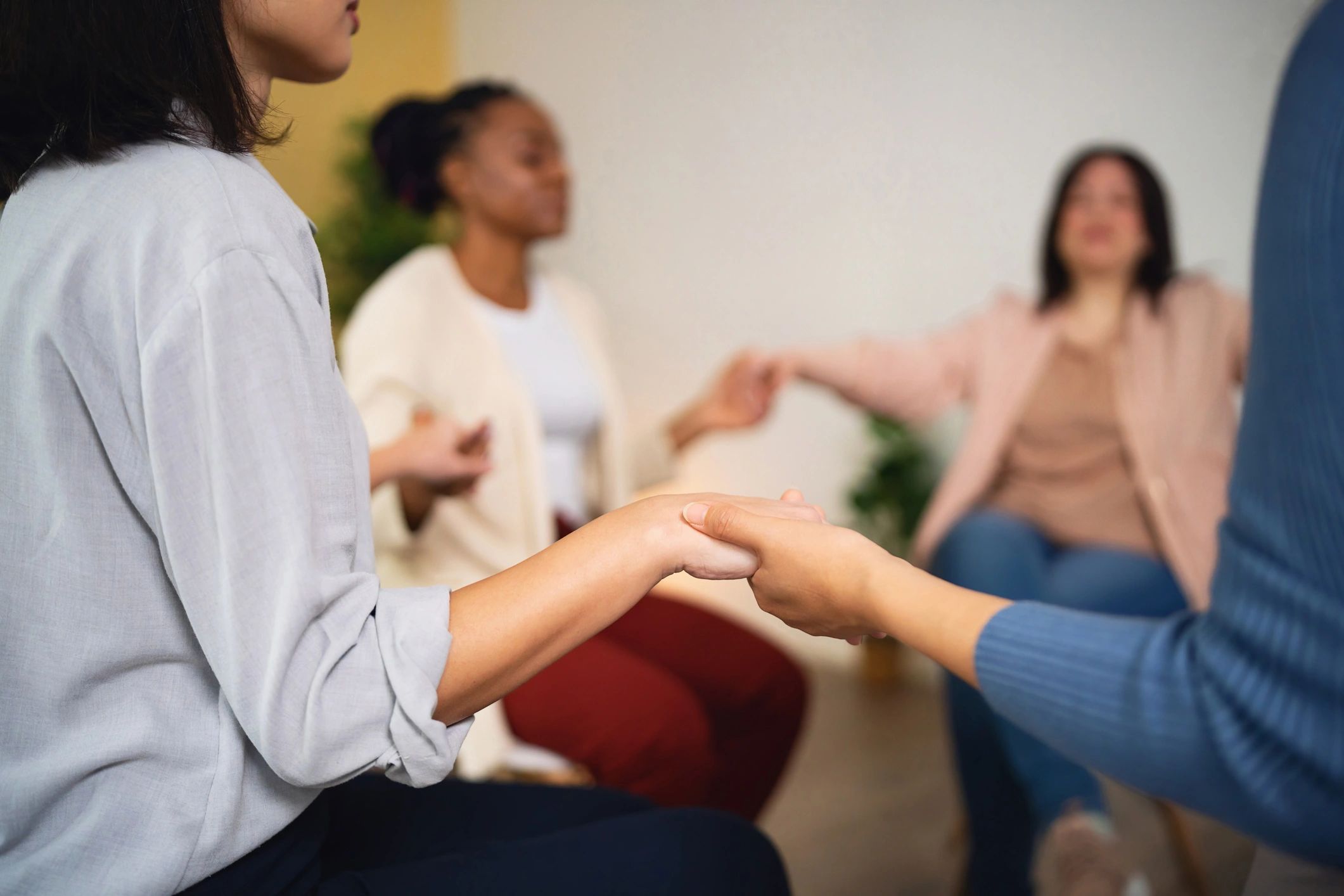 Support group participants holding hands in a circle